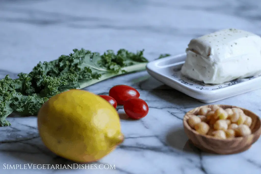 lemon, kale, tomatoes, garbanzo beans, and cheese on marble table