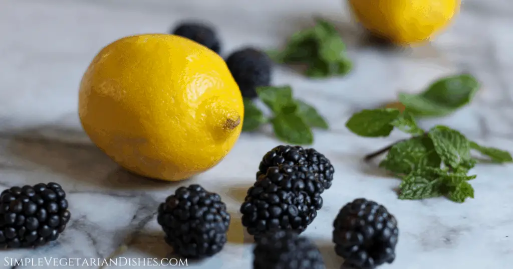 blackberries, mint, and lemon strewn across a marble table