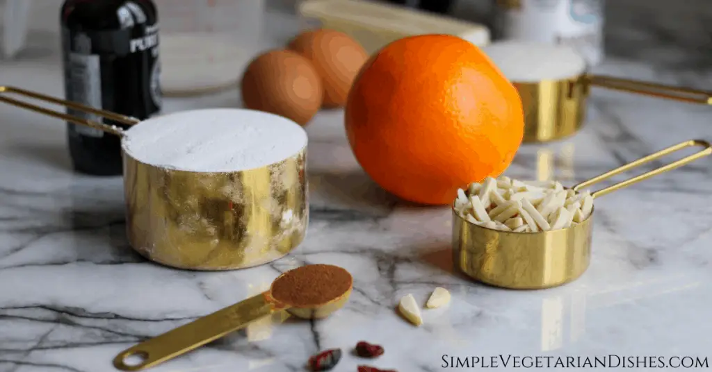 German muffin ingredients on marble table flour sugar butter eggs milk almonds cranberries orange