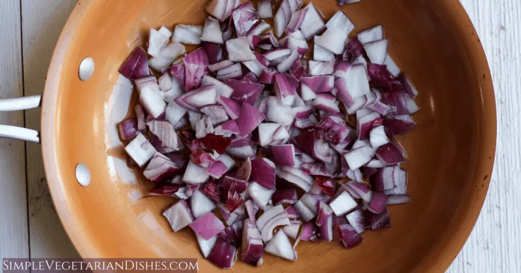 chopped red onions in copper skillet with olive oil
