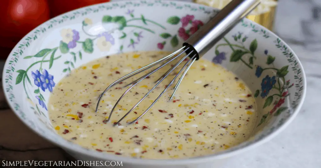 quiche filling in floral bowl with silver whisk