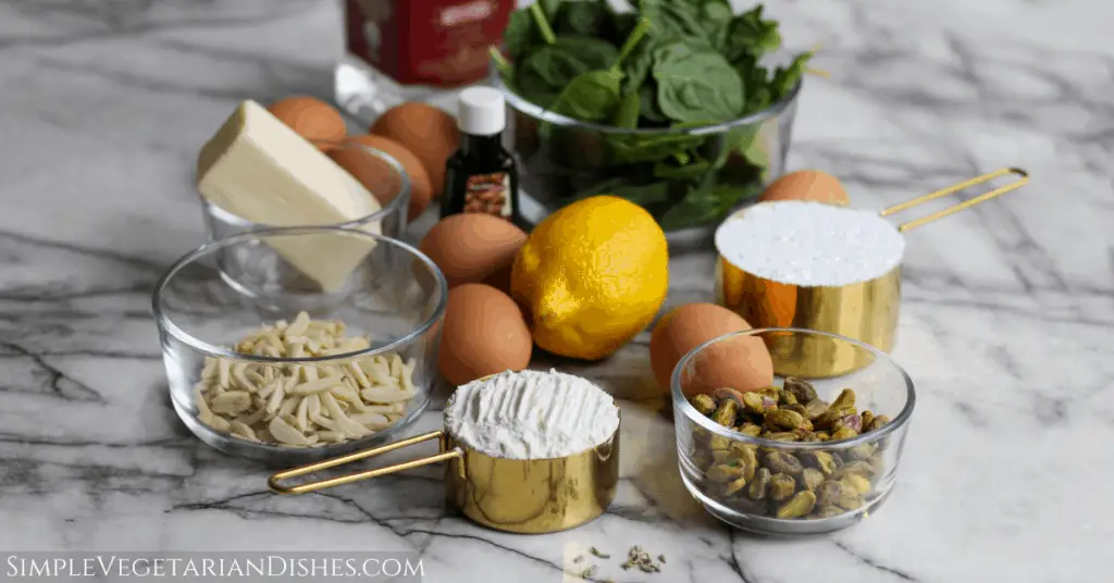 spinach, eggs, butter, pistachios, almonds, sugar, flour, lavender, almond extract, cherry liqueur on marble table
