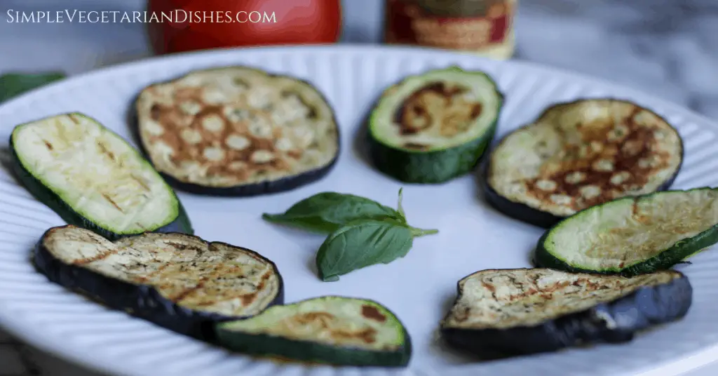 grilled vegetables on white plate with basil sprig