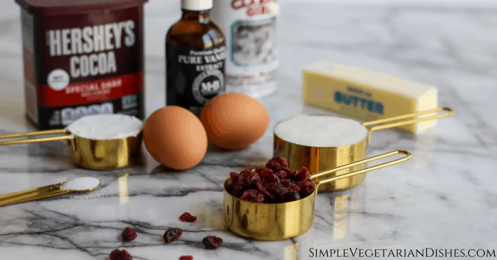 ingredients on marble table eggs cocoa flour sugar salt baking powder dried cranberries butter