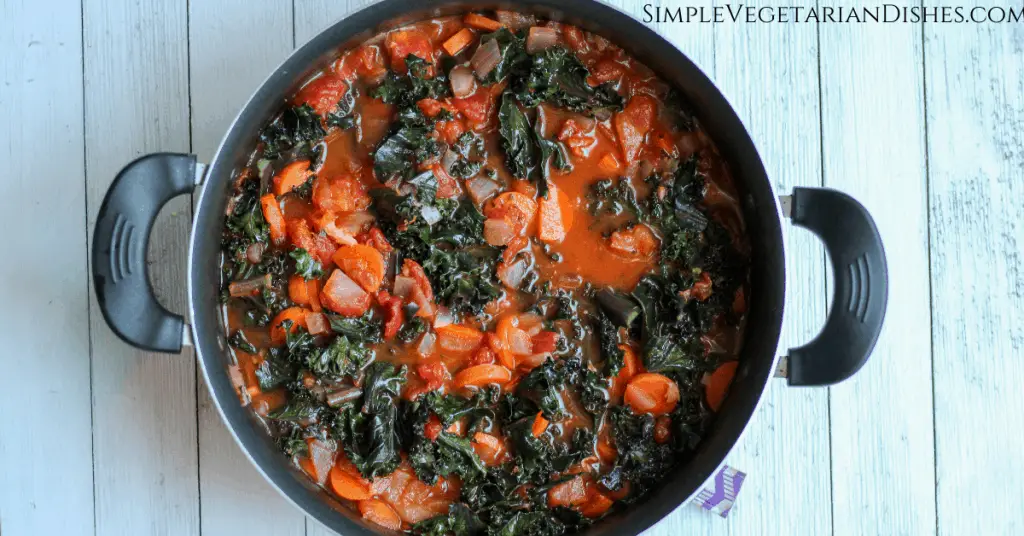 wilted purple kale in Mediterranean soup in dutch oven on white boards