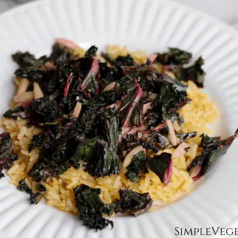 purple kale and slivered almonds on brown rice pilaf on white plate