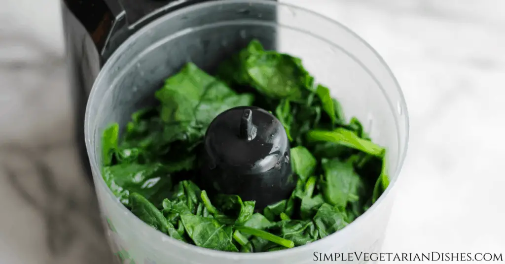 spinach in food processor on marble table