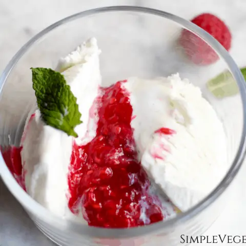 raspberry Melba sauce over vanilla ice cream in glass bowl, garnished with fresh mint on marble table