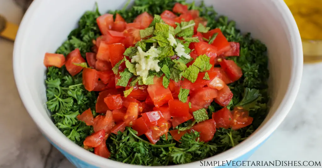 large mixing bowl with parsley tomatoes mint and garlic