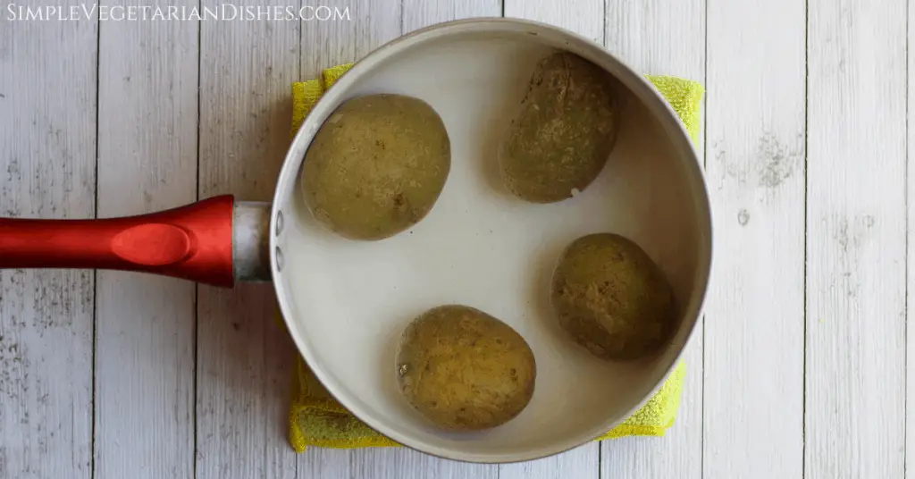 four Yukon gold potatoes in water in red saucepan
