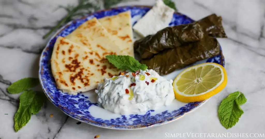 haydari served with dawali feta cheese and pita bread on blue china with lemon slice