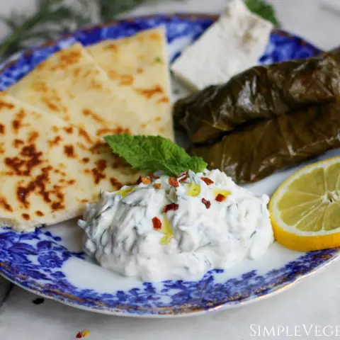 haydari served with dawali feta cheese and pita bread on blue china with lemon slice
