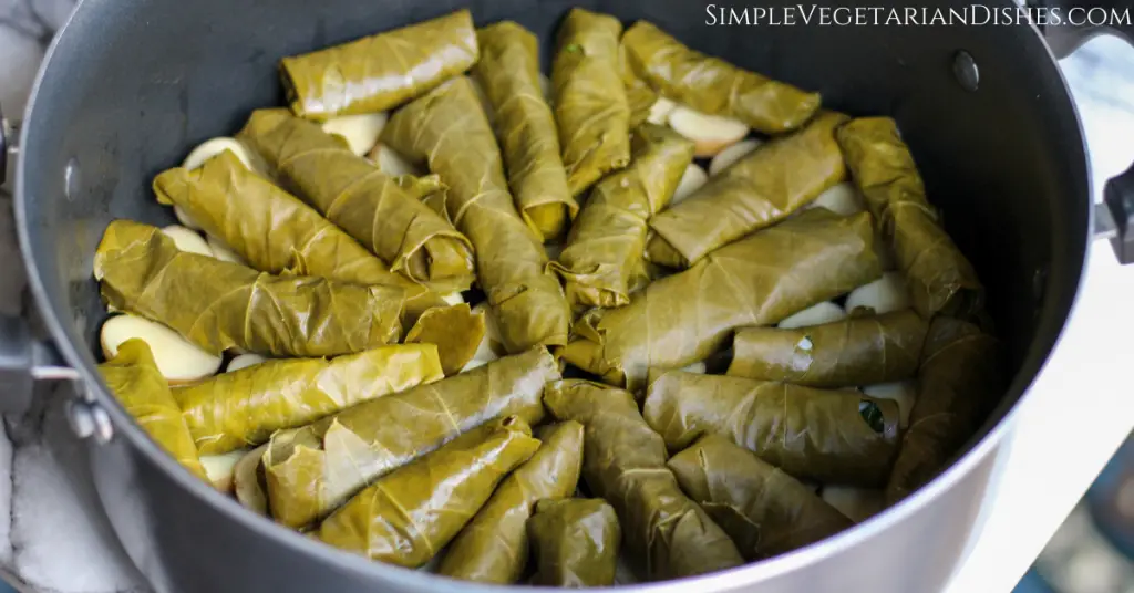 layer of stuffed grape leaves dawali over layer of potatoes in dutch oven