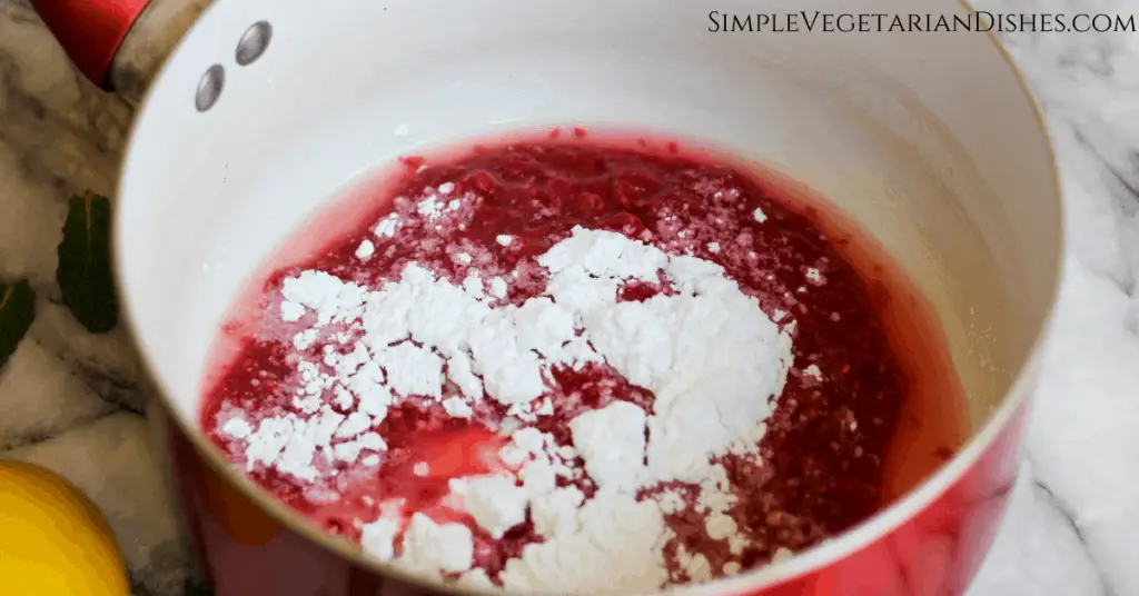 Melba sauce ingredients in red saucepan raspberry puree, powdered sugar, cornstarch and lemon juice