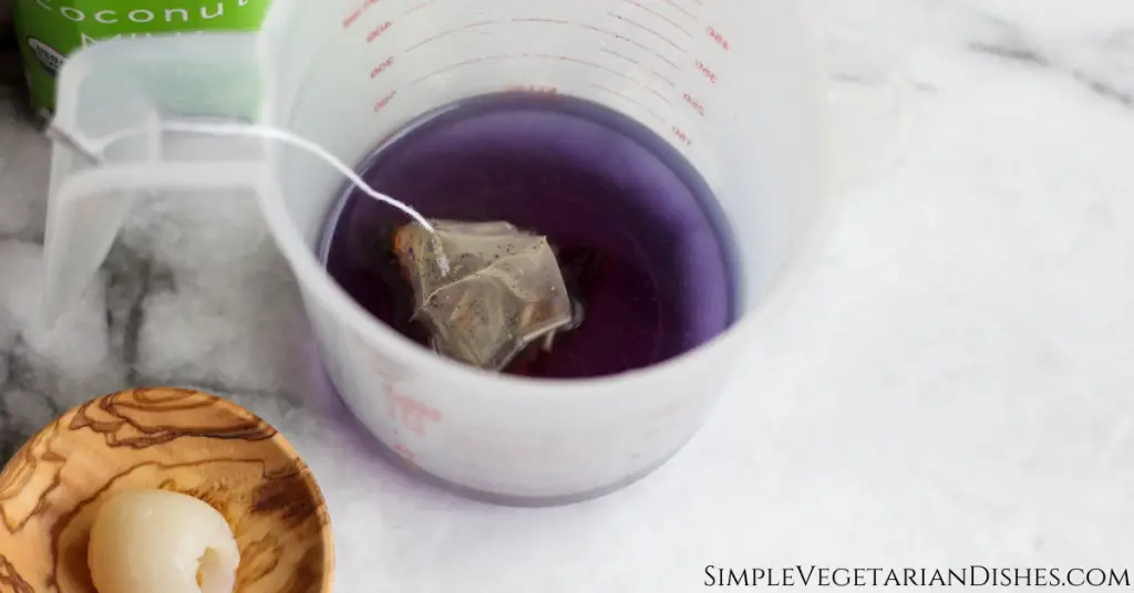 purple butterfly pea flower tea in measuring cup on white marble table