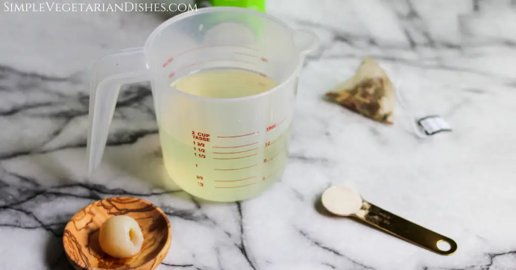 Lychee juice in measuring cup with golden teaspoon of agar agar powder