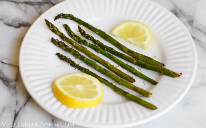 smoked asparagus served with lemon slices on white plate