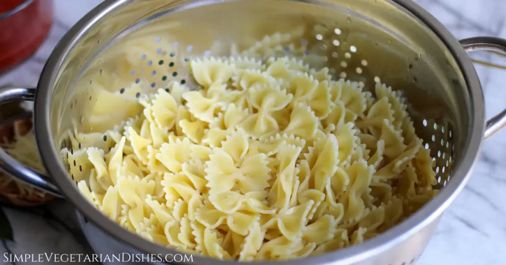 cooked farfalle pasta in stainless steel colander