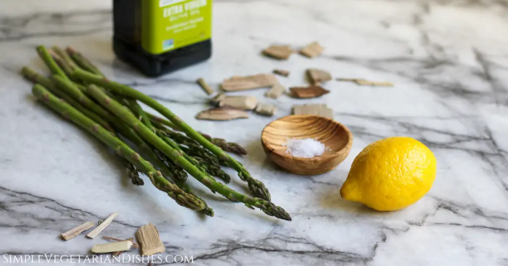 ingredients on white marble table hickory wood chips lemon salt asparagus olive oil