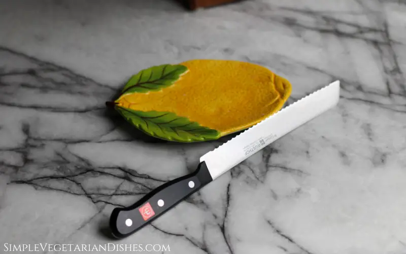 bread knife propped on lemon plate on white marble table