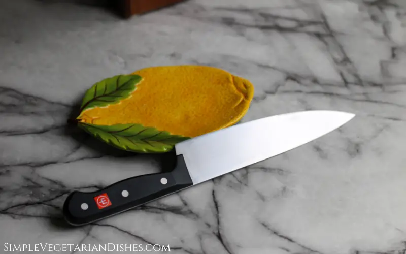 wusthof gourmet chef's knife propped on lemon plate on white marble table