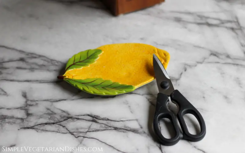 kitchen shears on white marble table propped on lemon plate