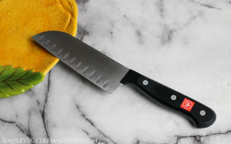 santoku knife on white marble table with lemon plate