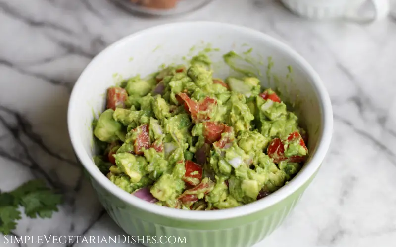 green bowl of guacamole to make tostaguac on white marble table