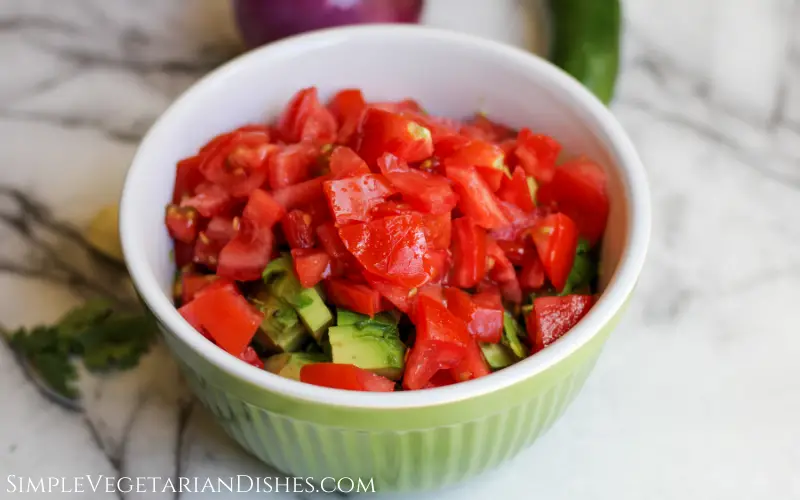 chopped tomatoes and avocados in green mixing bowl