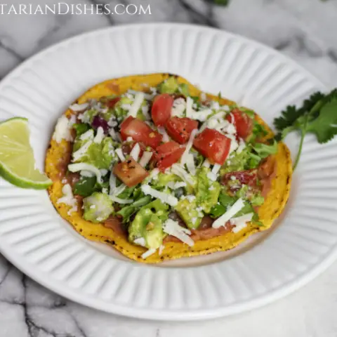 tostaguac served on white plate with lime and cilantro