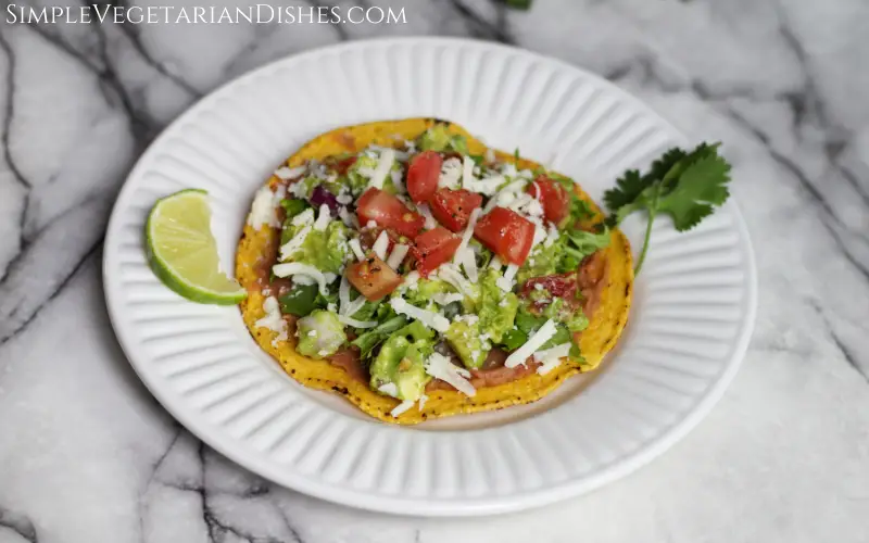 tostaguac served on white plate with lime and cilantro