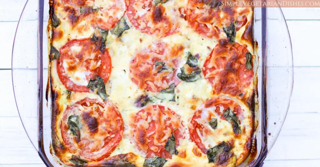 crustless tomato pie baked with browned cheese on edges, in glass dish on white board background