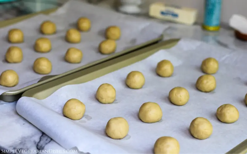 balls of cookie dough on parchment paper on gold cookie sheets