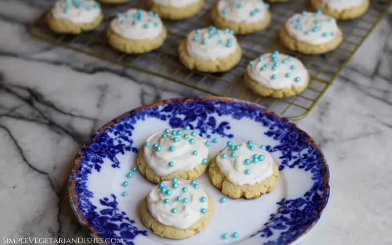 three high altitude sugar cookies on blue china with extra cookies in background