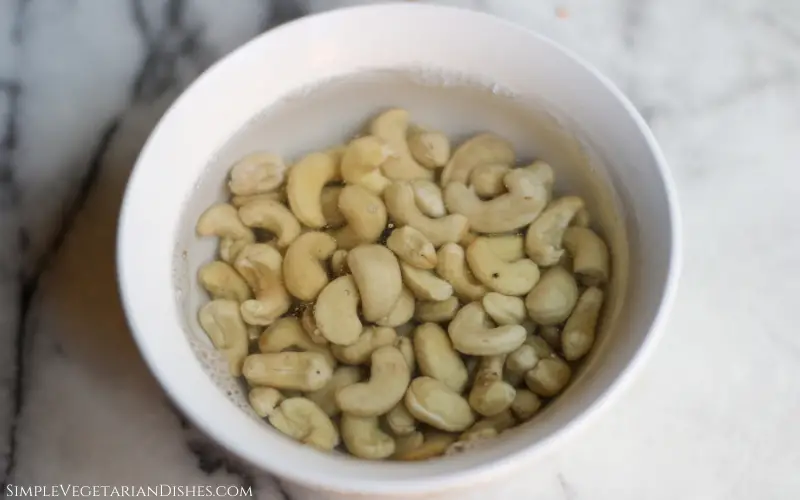 cashews soaking in hot water in white bowl
