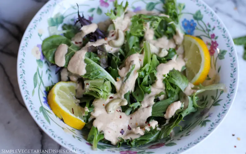 spicy cashew dressing on bed of greens with lemon wedges