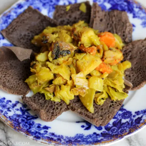 tikil gomen ethiopian cabbage served on injera on blue china