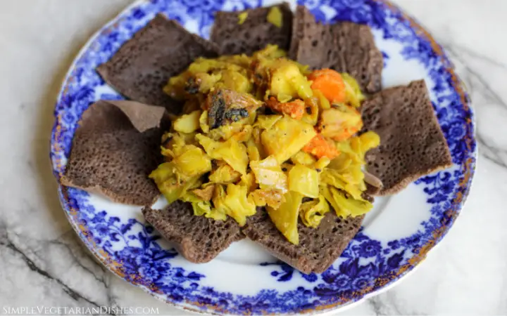tikil gomen ethiopian cabbage served on injera on blue china