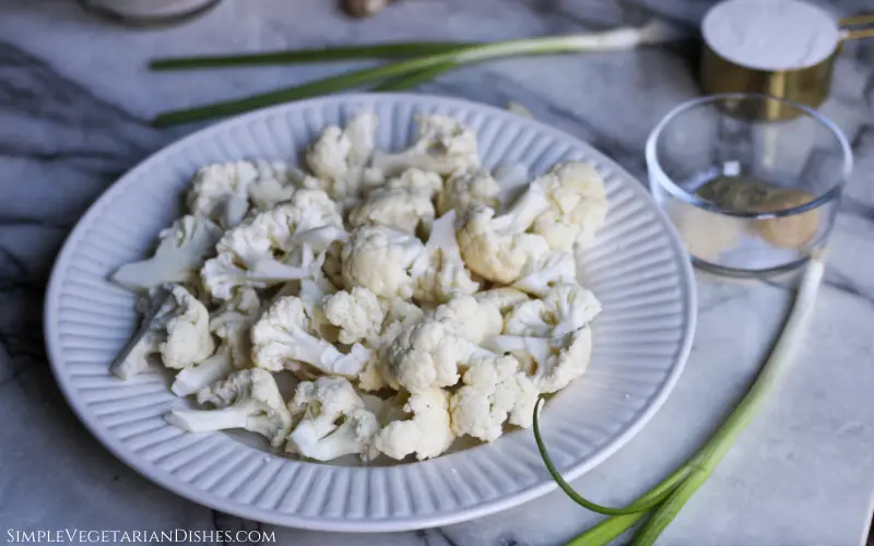 white plate of florets with green onions in background