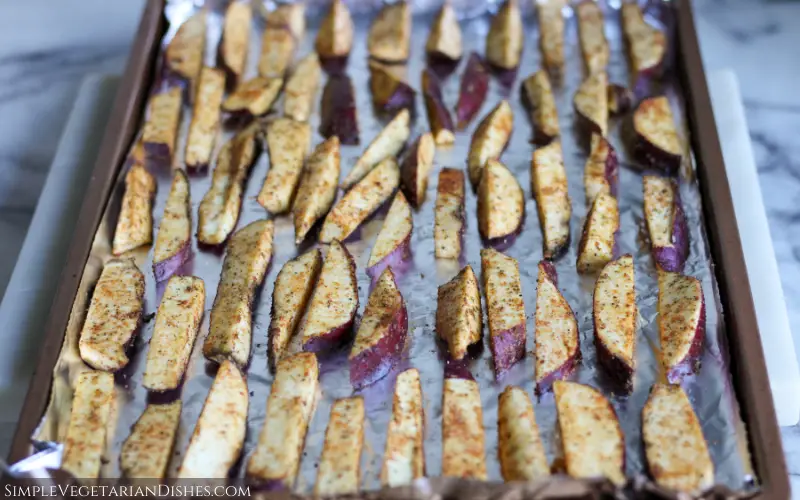 Korean sweet potato fries on foil lined baking sheet on marble cutting board