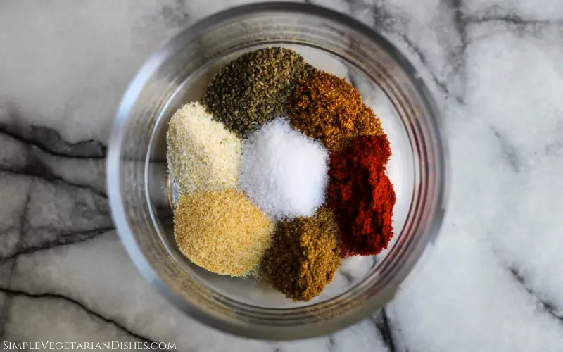 spices for cajun seasoning blend in small glass bowl on white marble table