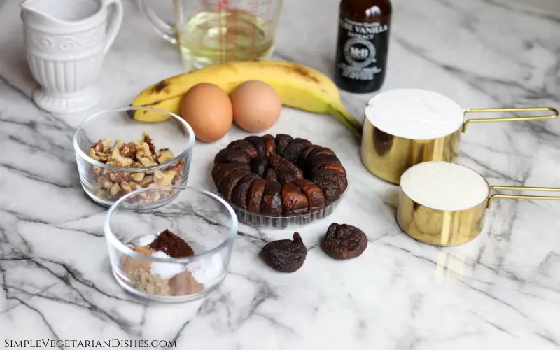 figs, egg, banana, flour, sugar, spices, walnuts, vanilla, oil, milk on white marble table