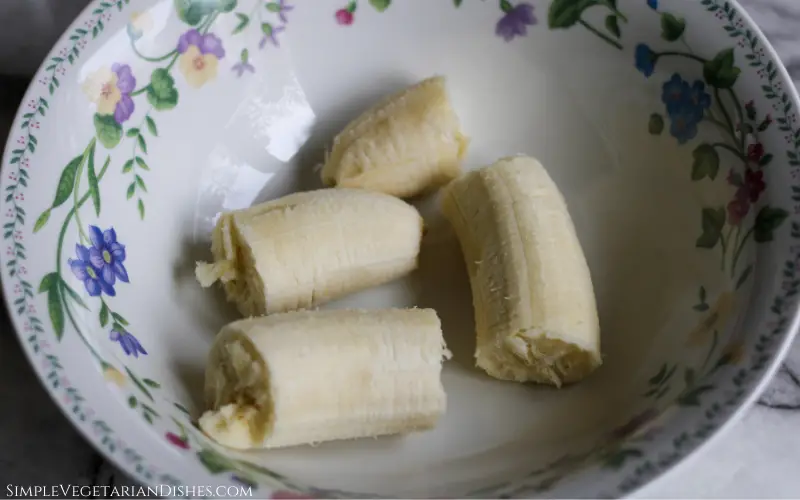 peeled banana broken into pieces in floral bowl