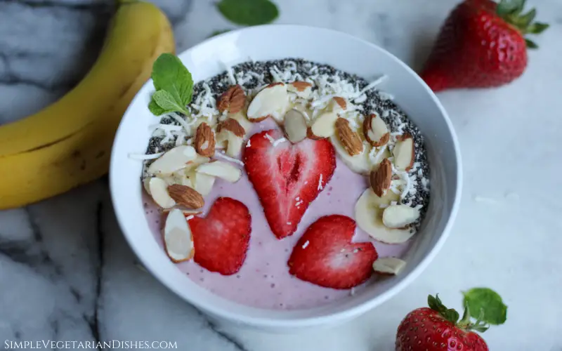 strawberry banana smoothie bowl topped with nuts and seeds