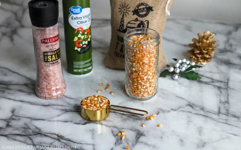 ingredients for air fryer popcorn kernels olive oil spray pink Himalayan salt on white marble table