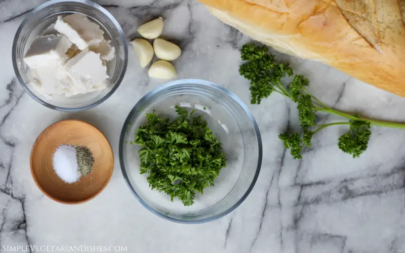 parsley butter garlic salt pepper baguette on white marble table