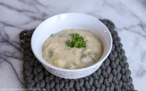 German potato soup in white bowl with sprig of parsley as garnish