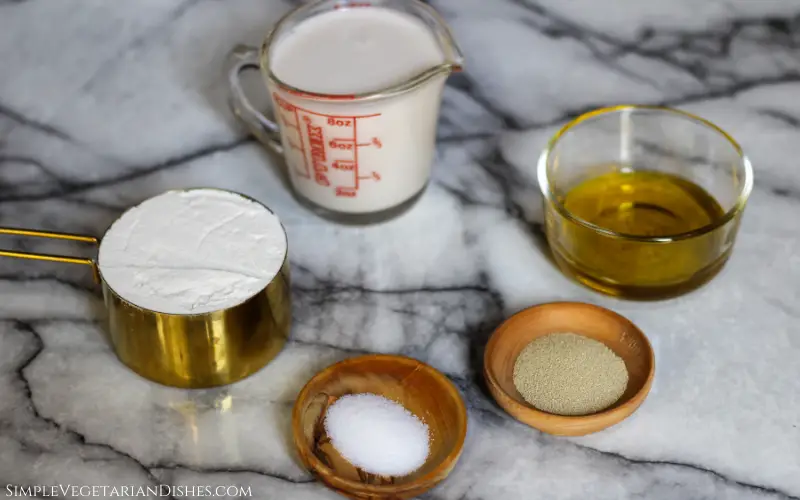 almond milk, flour, olive oil, salt and yeast on white marble table