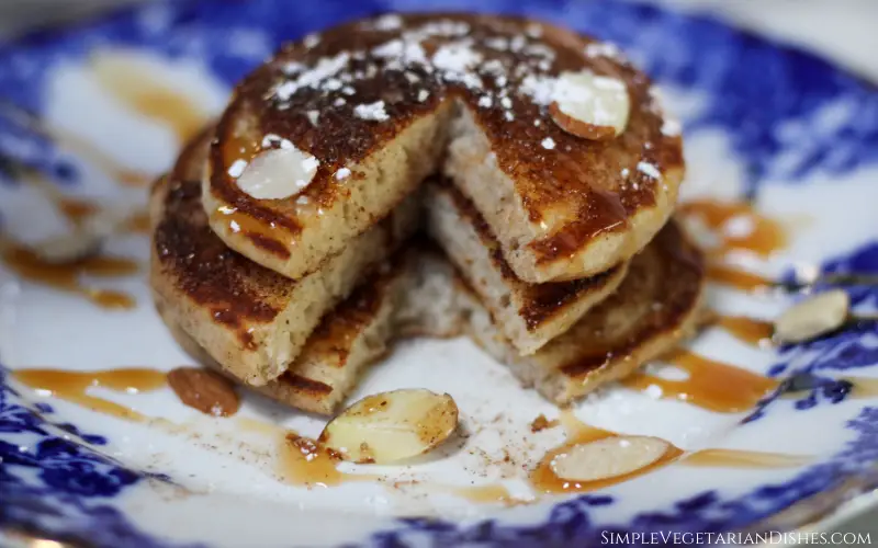 stack of churro pancakes served on blue china with bite removed