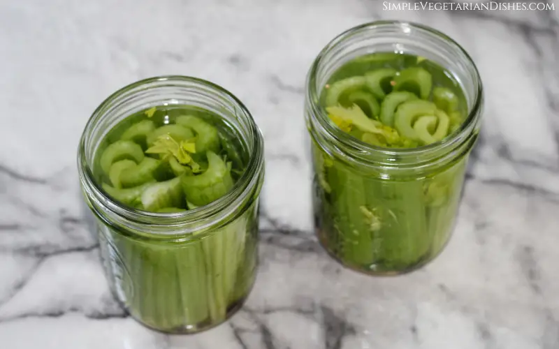 veggie sticks in brine in pint jars on white marble table